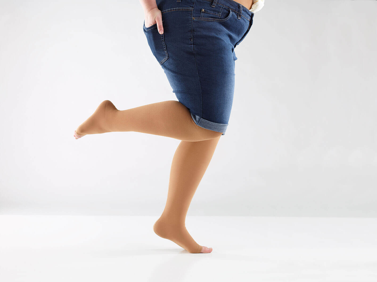 Bildausschnitt einer Frau mit kurzer Jeanshose und curaflow-Flachstrick Kompression von Bauerfeind an den Beinen.